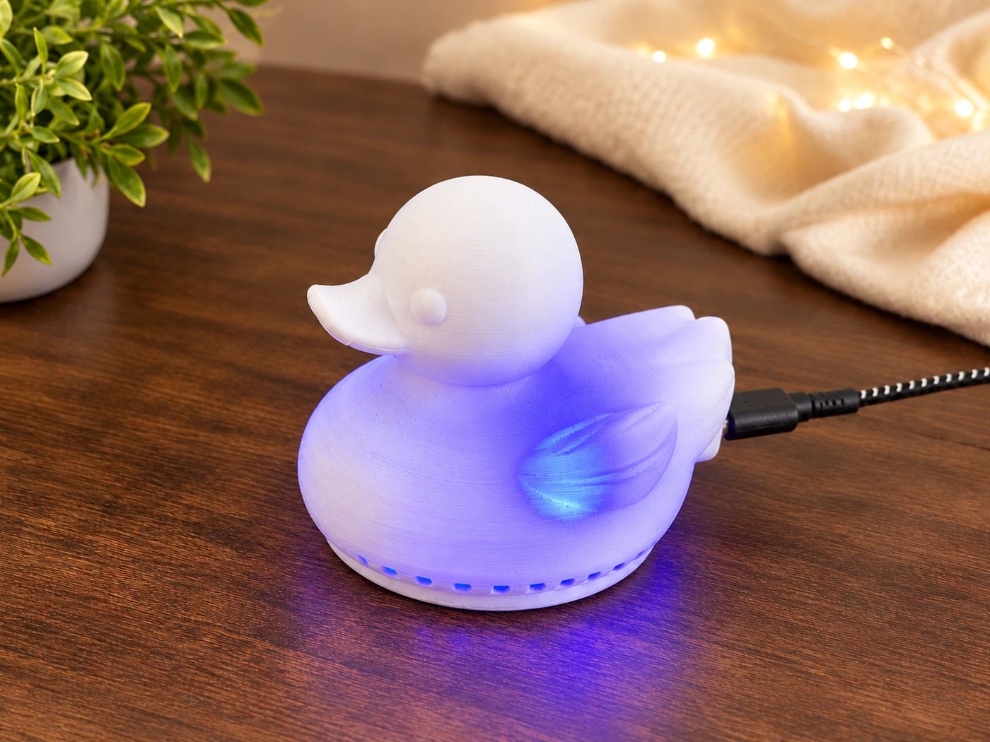 White AirQuality Duck glowing blue on a wooden desk